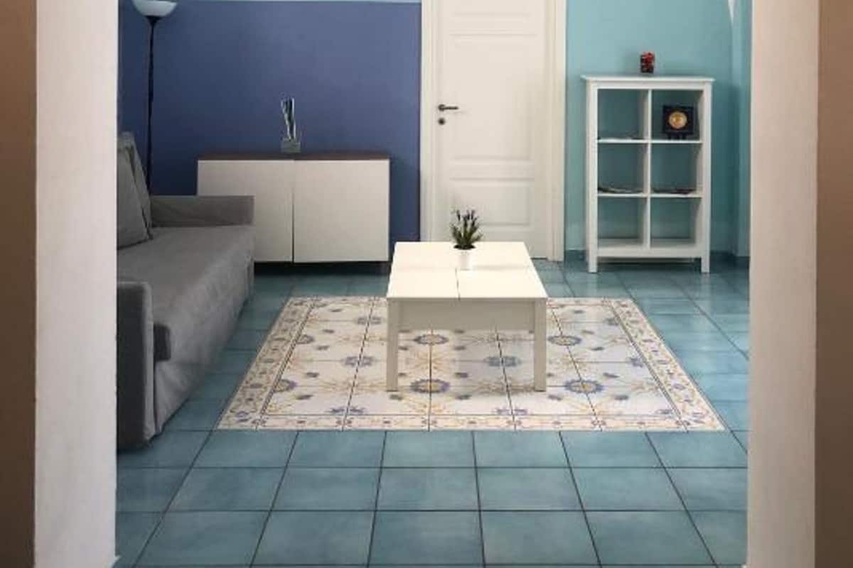 Um quarto com um sofá branco, uma mesa de centro branca e um tapete estampado.