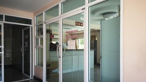 Un espace d’accueil doté de portes vitrées, d’un comptoir de réception et d’une signalétique dans une langue étrangère.