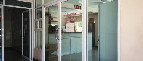 A reception area with glass doors, a reception desk, and a sign in a foreign language.