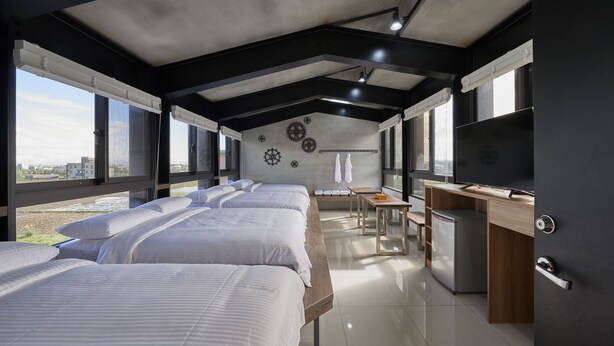 Een moderne hotelkamer met grote bedden, een bureau, een koelkast en een televisie.