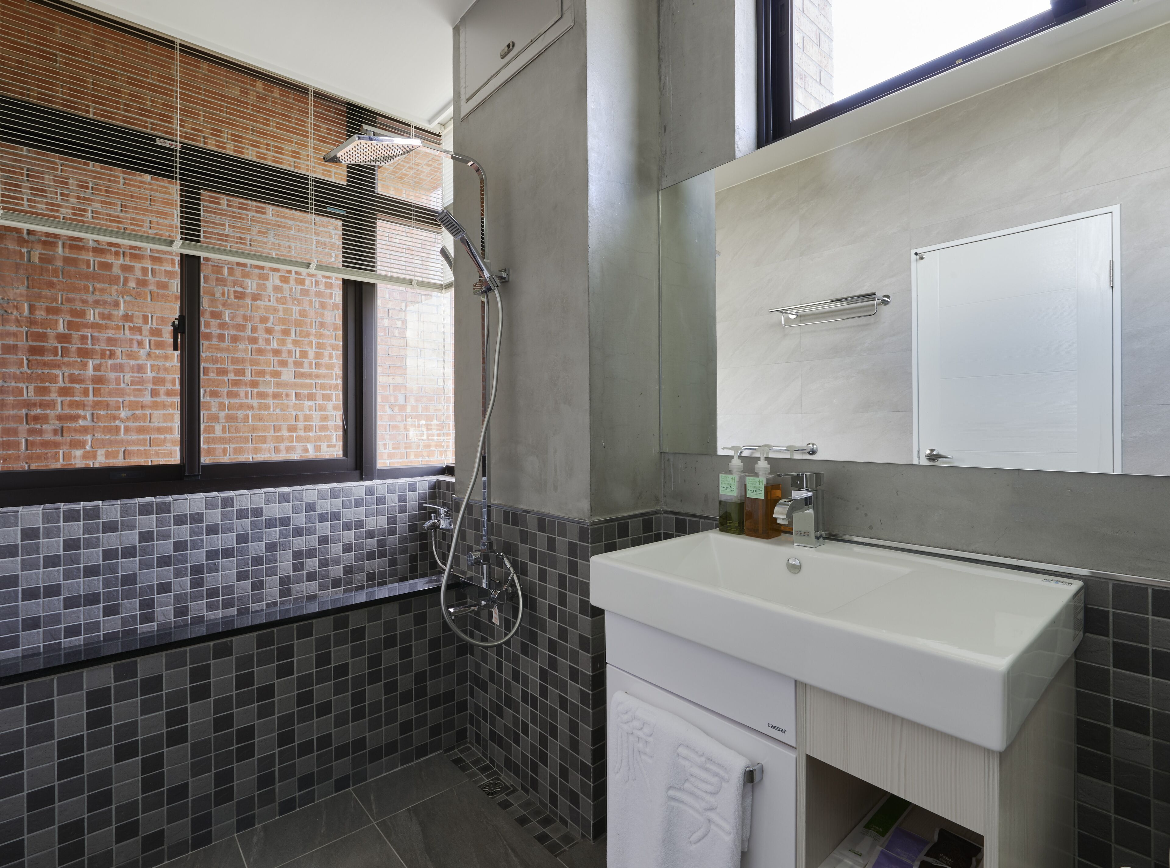Een moderne badkamer met een douche, wastafel en spiegel.