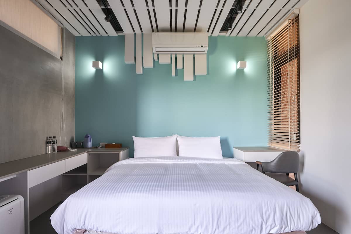 Una habitación de hotel moderna con una cama grande, un escritorio y una silla.