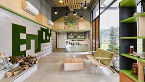 Een modern interieur met een receptiebalie, een houten salontafel, een groene stoel en uitzicht op de omgeving.