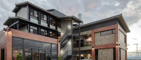 A modern two-story building with large windows, a staircase, and a white pickup truck parked in front.