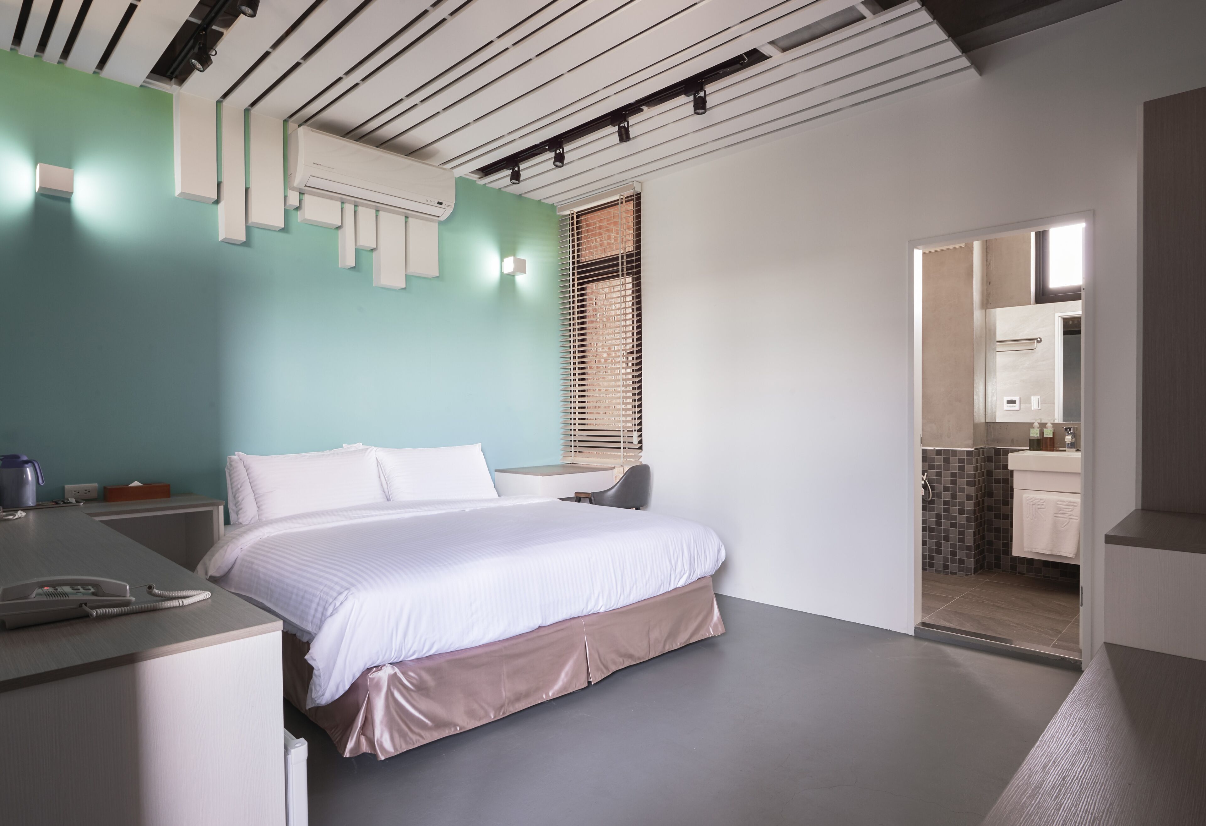 Une chambre d’hôtel moderne avec un lit, une table de chevet et vue sur la salle de bain.
