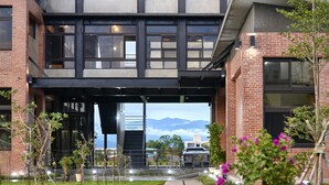 Een modern gebouw met een overdekte ingang, buiten zitplaatsen en uitzicht op bergen.