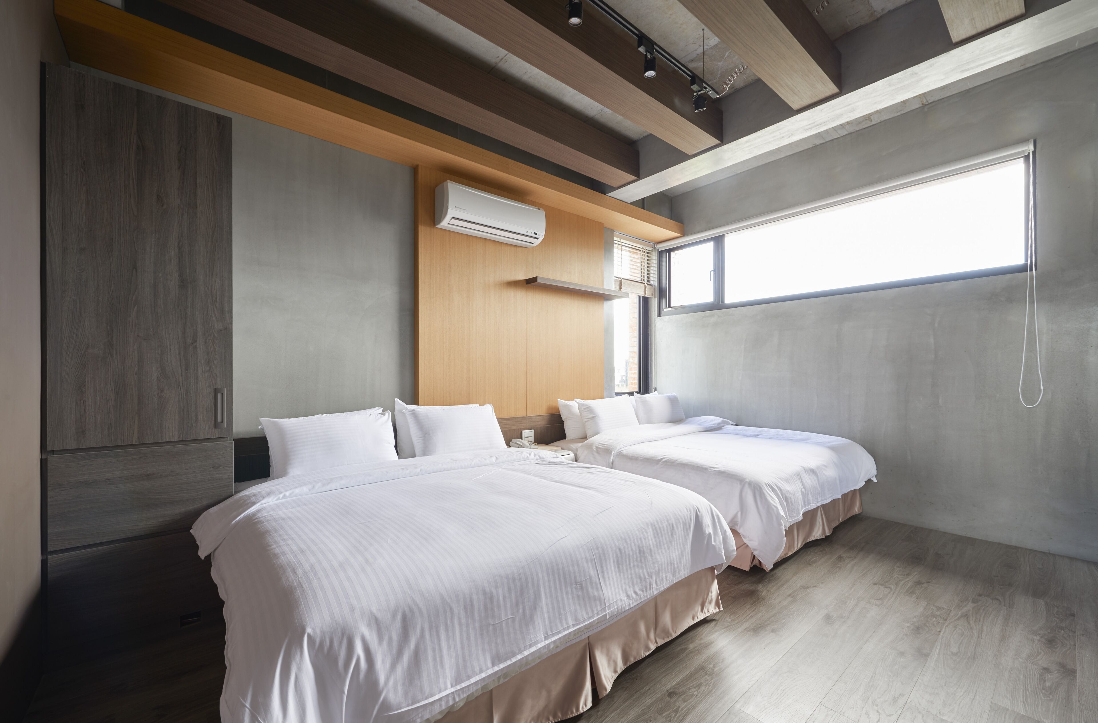 Una habitación de hotel moderna con dos camas, techo de madera y un ventanal grande.