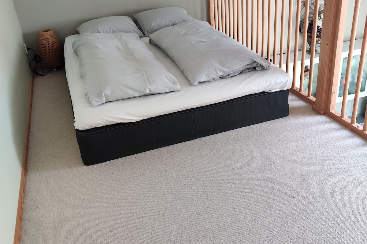 A bed with white bedding, a black mattress, and a wooden headboard.