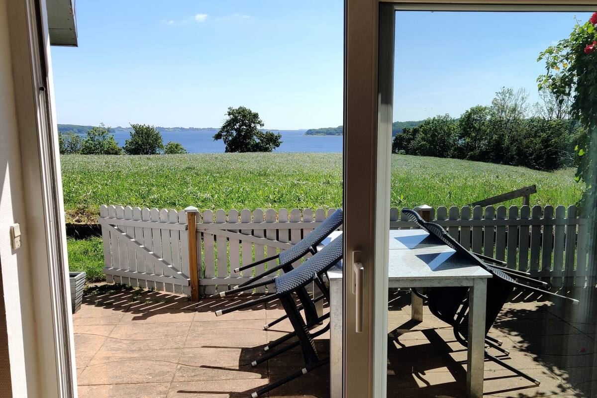 A sliding glass door leading to an outdoor patio with a white fence, a table, and chairs.