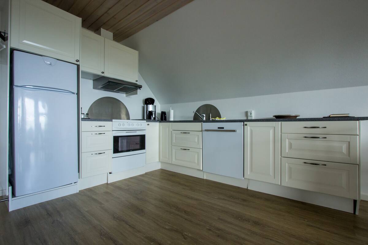 A modern kitchen with white cabinetry, a built-in oven, and a stainless steel refrigerator.