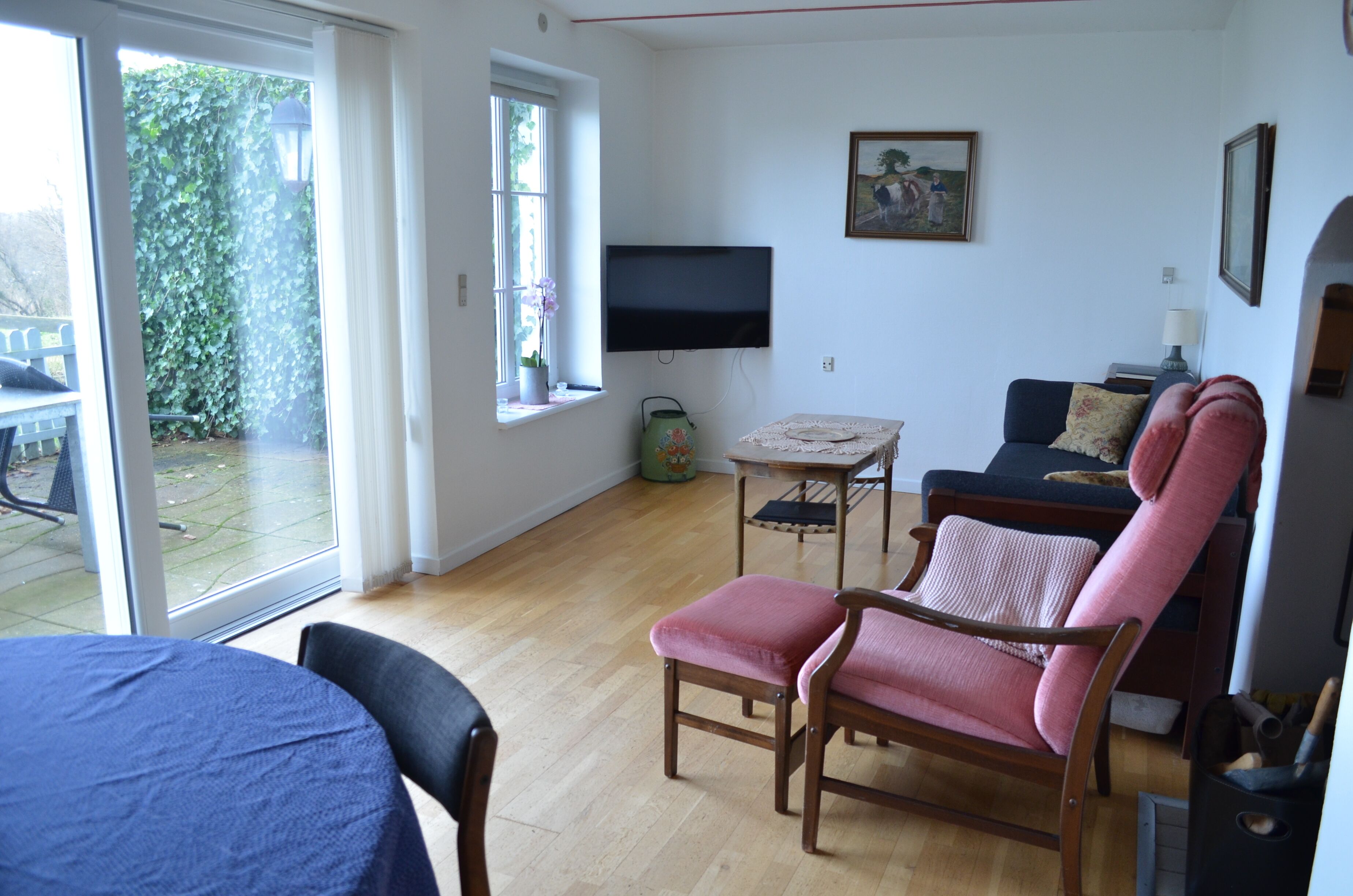 Un salon avec un téléviseur, un canapé, un fauteuil et une table.