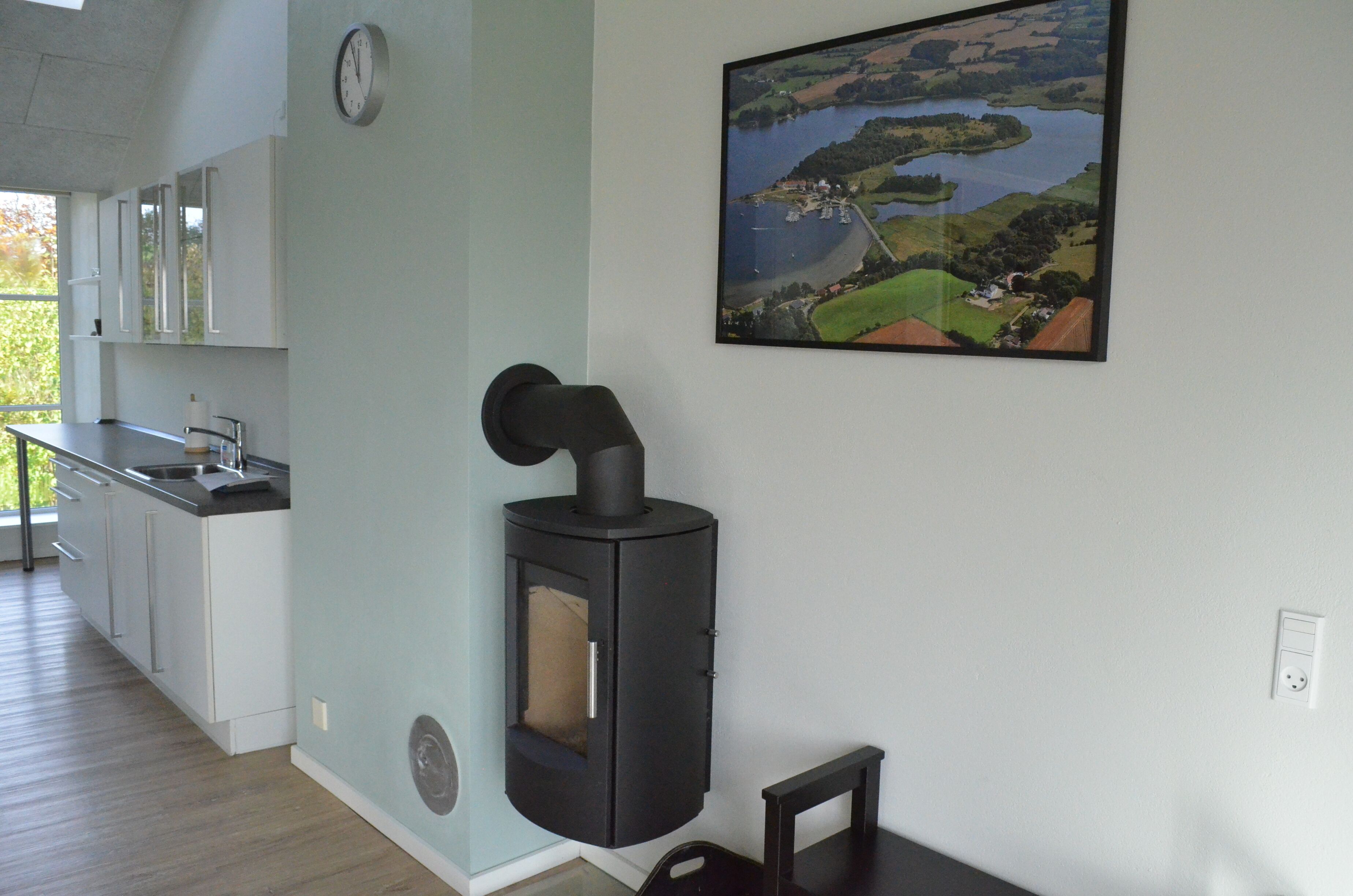 A modern kitchen with a built-in wood stove, a dining area with a table and chairs, and a large window overlooking a scenic landscape.