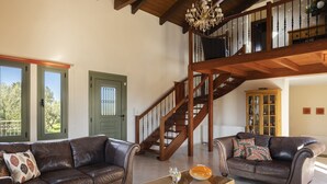 A spacious living room with leather sofas, a glass coffee table, and a wooden staircase. - Private pool and sea view (Leivathou)