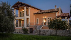 A two-story house with a balcony, a stone wall, and a staircase leading to the entrance. - Private pool and sea view (Leivathou)