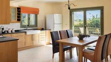 A modern kitchen with wooden cabinets, a white refrigerator, and a dining area with a wooden table and chairs.