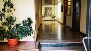 A hotel lobby with a marble staircase, potted plants, and a framed artwork on the wall. - St. Peter Area Luxury Suites (Rome)