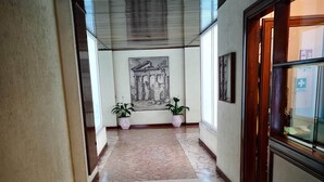 A hallway with a tiled floor, a ceiling with a metal grid, and a framed picture on the wall. - St. Peter Area Luxury Suites (Rome)