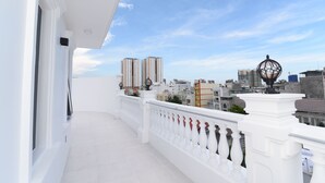 Un balcón con barandillas blancas y una vista despejada del paisaje urbano.