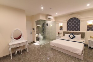 Un dormitorio moderno con una cama grande, un tocador con espejo, ducha con cerramiento de vidrio y pared con estampado.