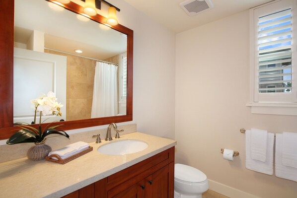A bathroom with a double sink vanity, a large mirror, a toilet, and a window with blinds.