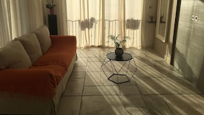 Een woonkamer met een bank, een rond bijzettafeltje en een potplant.