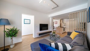 A modern living room with a sofa, a TV, a plant, and a lamp. - Holiday Home Apartments Bellamare (Zadar)