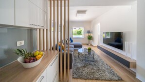 A modern living room with a sofa, a coffee table, and a TV. - Holiday Home Apartments Bellamare (Zadar)