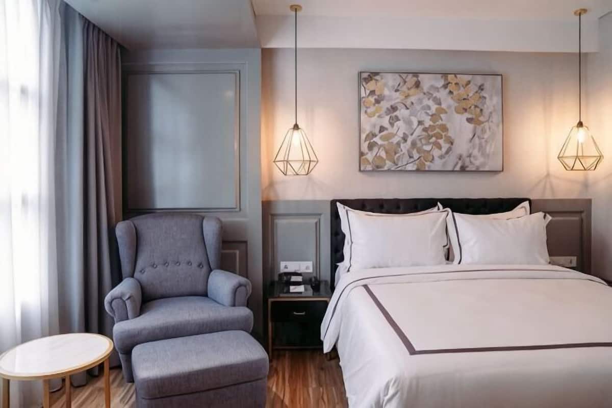 A hotel room with a bed, a chair, a small table, and a nightstand.