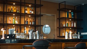 Zona de bar con taburetes, estantes de botellas de licor y un espejo.