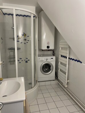 Ett badrum med dusch, tvättmaskin och element.