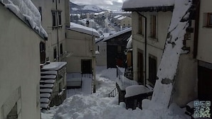 A narrow street with buildings on either side covered in snow, leading to a town in the distance. - Garnì B&B La Rua-Pescocostanzo (Pescocostanzo)