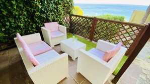 Un patio con mobiliario de mimbre y vista al océano.
