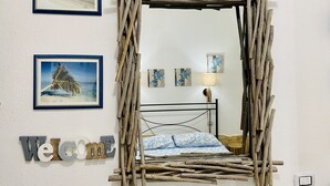 Una habitación con una cama, un espejo en la pared y cuadros enmarcados.