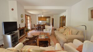 A living room with a television, sofa, coffee table, and a dining area with chairs and a table. - Holiday rental villa with swimming pool in Begur, Sa Tuna (Begur)