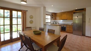 A spacious kitchen with wooden cabinets, a large island, and a built-in refrigerator. - Holiday rental villa with swimming pool in Begur, Sa Tuna (Begur)