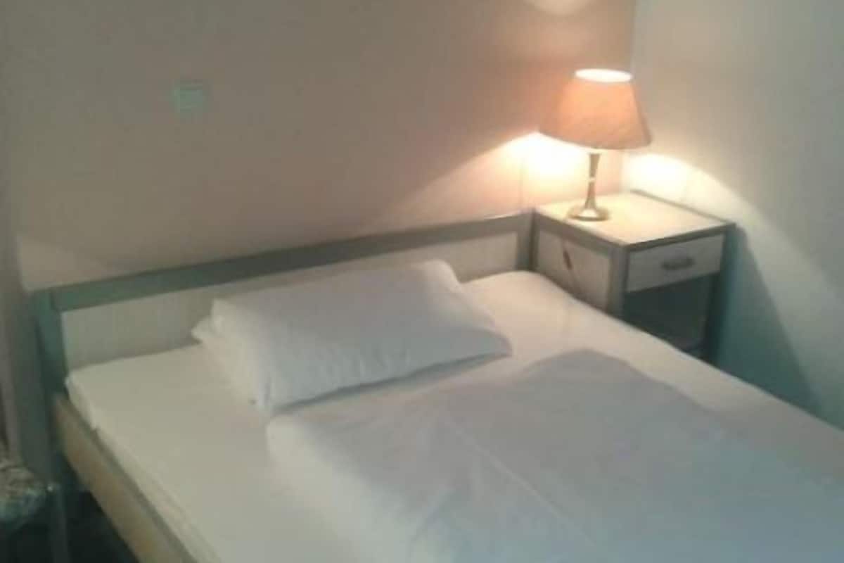 Ein Einzelbett mit weißer Bettwäsche in einem Hotelzimmer.