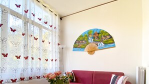 Un salon avec un canapé rouge, une table basse en verre et un vase rempli de fleurs.