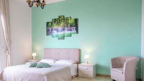 Une chambre à coucher comprenant un lit, des tables de chevet, une chaise et une œuvre d’art accrochée au mur.