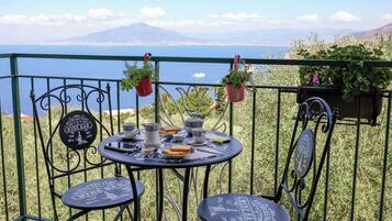 Una terraza con una mesa dispuesta para el desayuno, con vistas panorámicas al agua y a las montañas.