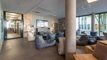 A modern interior with seating areas, a large pillar, and a visible corridor leading to another room.