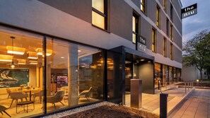 A modern building with a glass facade, a sign reading "the niu", and outdoor seating area. - Holiday Inn - the niu, Timber Esslingen by IHG (Esslingen)