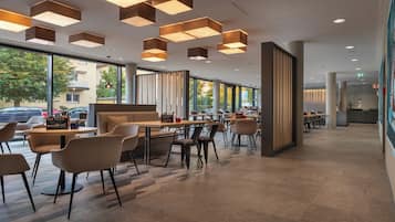 Un café moderne doté d’un espace salon central, de grandes fenêtres et d’un design contemporain au niveau du plafond.