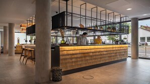 A modern bar area with a wooden counter, metal shelving, and a view of the street outside. - Holiday Inn - the niu, Timber Esslingen by IHG (Esslingen)