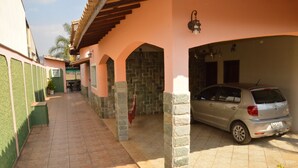 Un espacio al aire libre cubierto con un coche estacionado debajo de un edificio de pilares de piedra y suelo de baldosas.