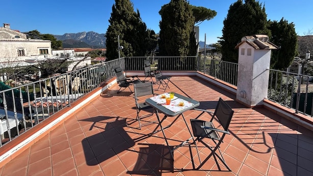 Una terraza con una mesa lista para dos personas, dos sillas y una pequeña estructura blanca.