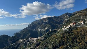 Un pueblo costero con edificios en una ladera, cielo despejado y vista al mar.