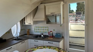 Cocina con gabinetes blancos, una estufa y una ventana a la derecha.
