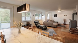 A spacious living area with a dining table, sofas, and a fireplace. - House with 147m², Sauna, Hot Tub, Terrace, garden, BBQ & WLAN (Reinerzau)