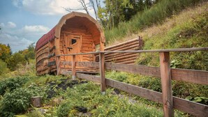 A wooden log cabin with a red roof, surrounded by lush greenery and a wooden fence. - House with 147m², Sauna, Hot Tub, Terrace, garden, BBQ & WLAN (Reinerzau)