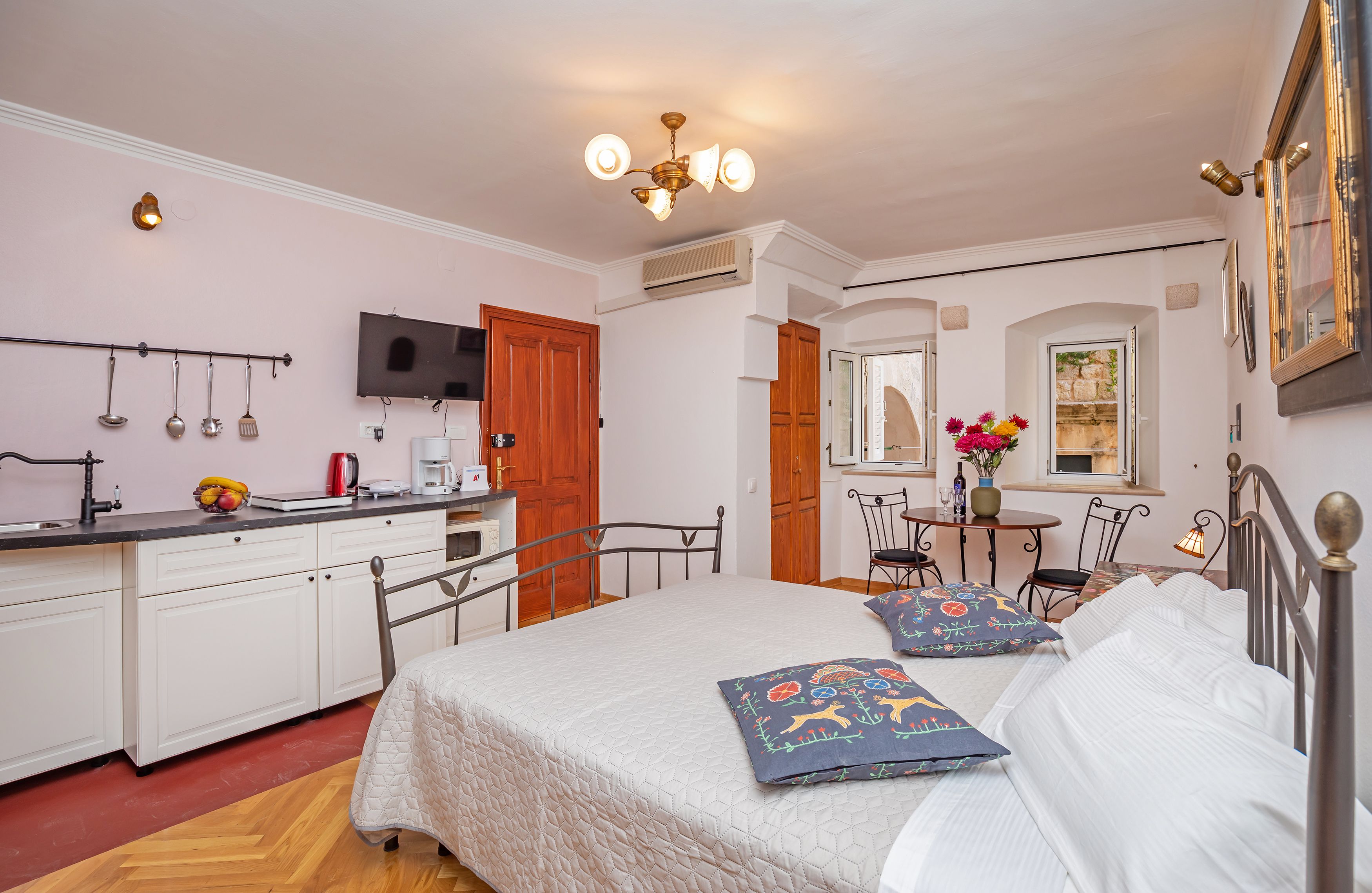 A bedroom with a bed, bedside tables, a desk, and a chair. There is a window with a view of a building.